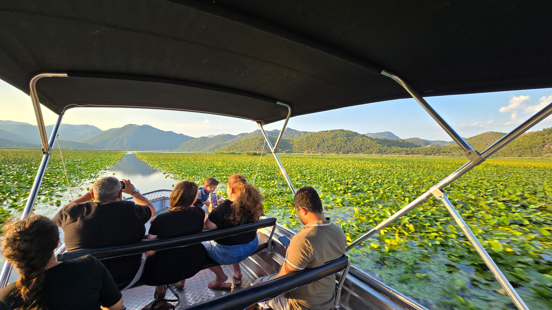 Family on a private boat cutting through water lilies on Skadar Lake