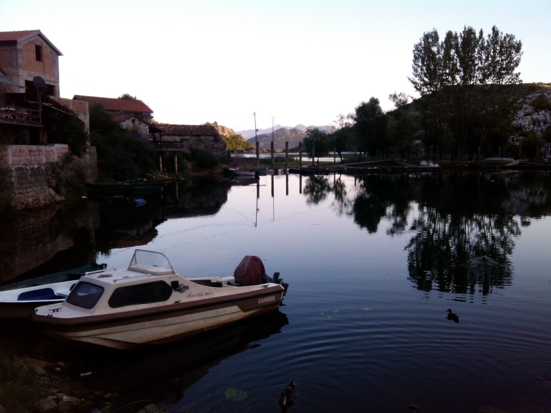 Fishing boats moored beside stone houses on the Karuč waterfront, Skadar Lake