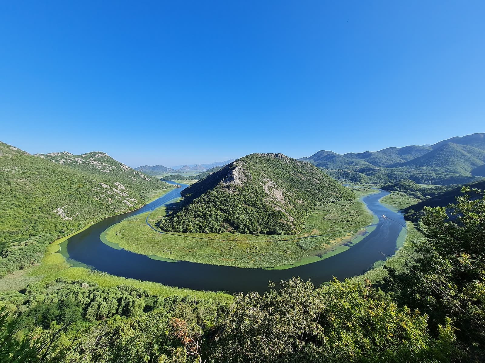 Pavlova Strana viewpoint over the horseshoe bend of the Crnojevića River, with green floating vegetation along the water